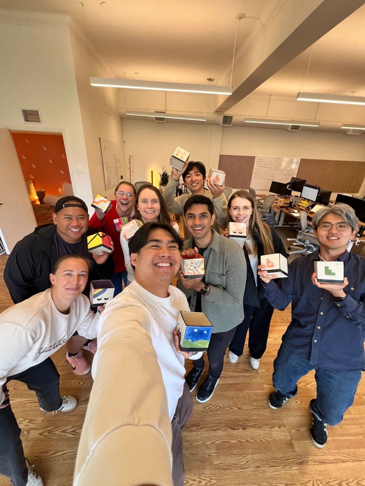 The team holding the tiles they painted at our quarterly offsite